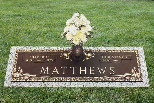 Matthews bronze memorial marker with garden rose and rock edge detail on a granite base.